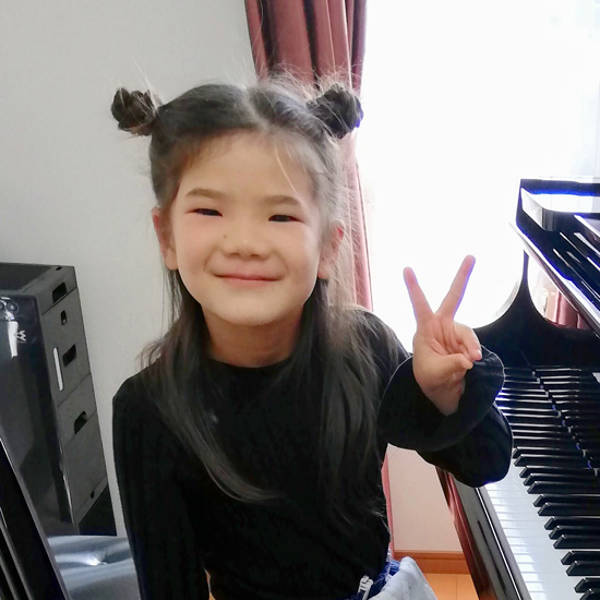 ピアノの前でピースする女の子の生徒写真１